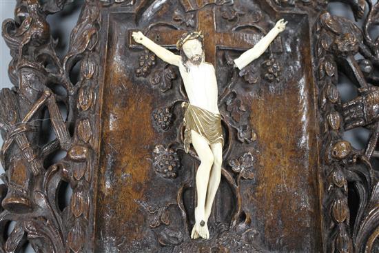 A 19th century European carved walnut and ivory crucifix, the ivory Corpus Christi on a pierced plaque decorated with angels, scrolls a